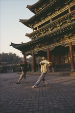 CHINA, General, Tai Chi, Two men doing morning exercises outside Buddhist temple