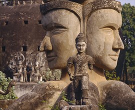 LAOS, Vientiane, Wat Xieng Khwan or the Buddha Park.  Giant twin heads with small statue in the