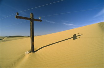 EGYPT, Western Desert , Telegraph pole almost covered by sand dune.