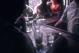 CUBA, Havana, Men and women sitting at a bar drinking Rum Moquito