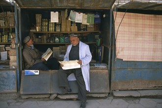 CHINA, Xinjiang , Kashgar, Muslim men reading at bookstall.