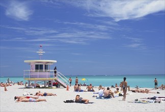 USA, Florida, Miami, Sunbathers on the beach by a colourful lifeguard hut