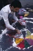 INDIA, Delhi , Painting patterns on ground as base for bonfire during Hindu Holi Festival.