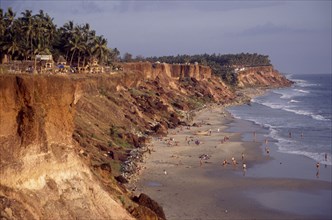 INDIA, Kerala, Varkala , "Coastline and narrow sandy cove with sunbathers sheltered by steep,