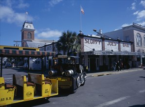 USA, Florida,  Key West , Duval Street. Sloppy Joes Bar and Tourist Train traveling along road