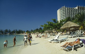 WEST INDIES, Jamaica , Ocho Rios , Sunbathers on the beach with hotel behind