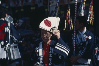 JAPAN, Honshu, Miyajima, Woman at the autumn Sake Festival holding a fan with the design of the