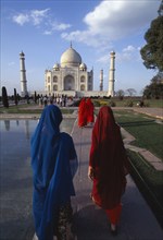 INDIA, Uttar Pradesh, Agra, The Taj Mahal with women in saris walking towards it beside the pool