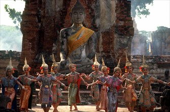 THAILAND, Ayutthaya, Temple dancers performing below a statue of Buddha in the ruins of the old