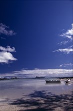 MAURITIUS,  , Grande Gaube, Sandy Beach with moored Boats and an Island in the distance with blue