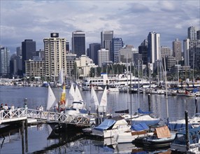 CANADA, British Columbia, Vancouver, City skyline over busy yacht harbour with people walking on