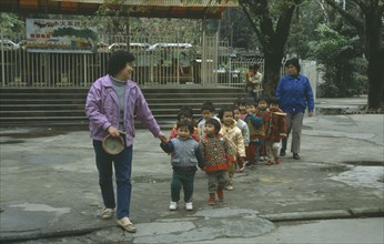 CHINA, Guangzhou , Children, Line of nursery school children with teachers on outing to park.