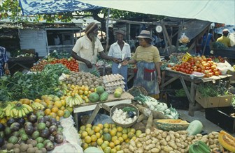 WEST INDIES, Jamaica, Montego Bay, Two women buying fruit from vendor in market