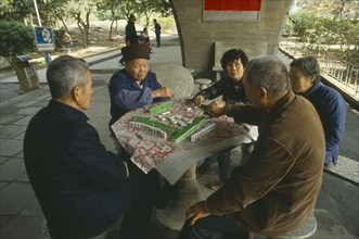 CHINA, Guangzhou,  Men and women sat around table playing Mahjong