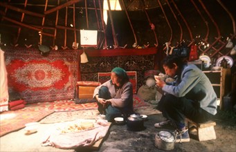 CHINA, Xinjiang, Tianchi, Interior of Kazak yurt with adult couple having a meal