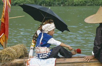 CHINA, Guizhou Province, Festival, Young boy in costume sitting under umbrella on dragon boat