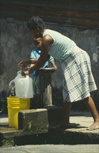 WEST INDIES, St Lucia, Soufriere, Woman and young boy collecting water from outside stand pipe
