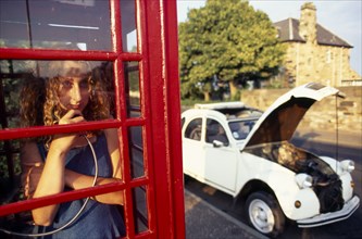 COMMUNICATIONS, Telephone, Phone Box, Girl making a call in a traditional red phone box with broken