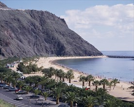 SPAIN, Canary Islands, Tenerife, Las Teresitas. Long sandy bay beneath black cliffs and palm lined