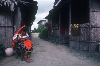 PANAMA,  , San Blas Islands, Cuna Indian woman sitting outside huts working on embroidery