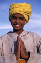 INDIA, Punjab, Amritsar , Portrait of smiling Sikh boy wearing yellow turban making gesture of