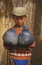 CHINA, Gansu, Xiahe, Tibetan boy wearing boxing gloves