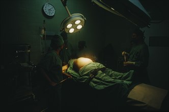 CUBA, Havana, Woman in labour lying on an operating table at the maternity hospital with lamps