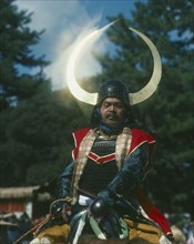 JAPAN, Honshu, Kyoto, Man on horseback in a Samuri Costume with the sun reflecting off his horned
