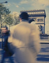 FRANCE, Ile de France, Paris, "Arc de Triomphe with people, blurred in action on the street in the