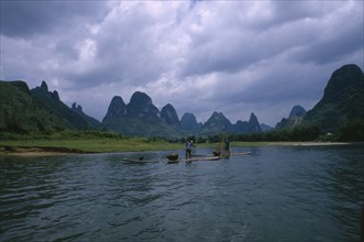 CHINA, Guangxi, Guilin, Cormorant fishermen on rafts on the River Li with limestone karst mountains