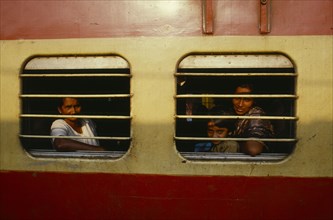INDIA, Kerala, Cochin, Passengers at barred windows of train carriage.