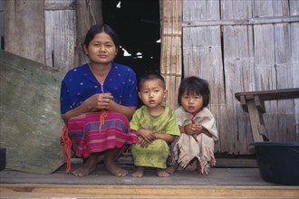 THAILAND, North, Mae Lui, Karen refugee mother and two children squat outside house