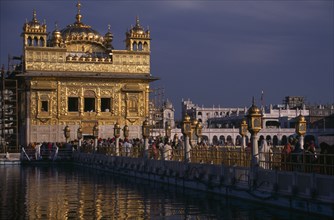 INDIA, Punjab, Amritsar, The Sikh Golden Temple with people on the walkway across the water