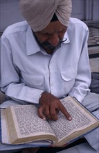 INDIA, Punjab, Amritsar, Man reading Sikh holy book at the Golden Temple.