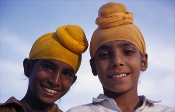 INDIA, Punjab, Amritsar, "Two Sikh boys.  Head and shoulders portrait, smiling."
