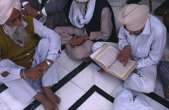 INDIA, Punjab, Amritsar, Group of elderly men reading Sikh holy book at Golden Temple sitting on