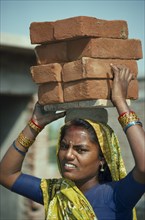 INDIA, Bihar, General, Woman carrying pile of bricks on her head
