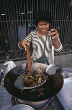 THAILAND, Bangkok, Woman cooking insects in a wok at a market stall