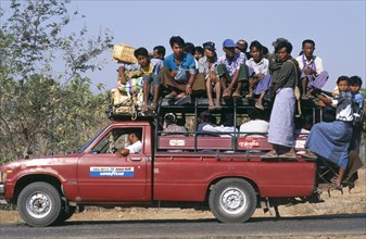 MYANMAR, Bagan, Overcrowded country minibus with people on the roof and hanging of the back  Burma