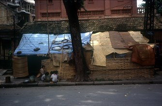 VIETNAM, Hanoi, Slum housing by roadside with group of small children outside entrance.