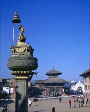 NEPAL, Bhaktapur, Main square with temple and gold statue on tall plinth.