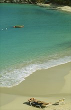 WEST INDIES, St.Martin, Grande Case Beach, Man sunbathing on sun lounger by the water’s edge