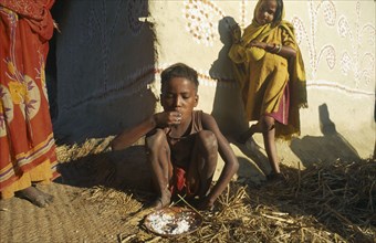 INDIA, Bihar, Myapur, "Boy in Ganges Plain village eating rice with his hands, little girl leaning