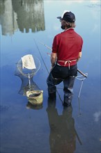 10045577 SPORT  Fishing Man river fishing standing in waders.
