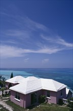 BERMUDA, Somerset, Clifftop house. Purple painted exterior with white roof and view out to sea.