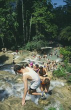 WEST INDIES, Jamaica, Ocho Rios, Tourists help each other up to the top of Dunns River Falls