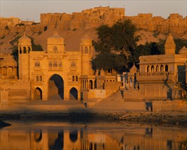 INDIA, Rajasthan, Jaisalmer, Gadi Sagar Tank  with buildings the Fort in the background