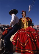 SPAIN, Andalucia, Seville, Couple in Flamenco costume riding horseback at the April Fair in Los
