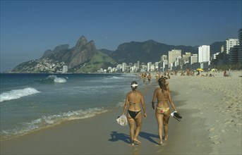 BRAZIL, Rio de Janeiro, Girls walking along Ipanema beach.
