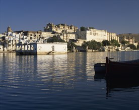 INDIA, Rajasthan, Udaipur, City Palace with reflections and silhouetted boat